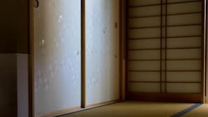 Une pièce de style japonais traditionnel, avec un sol recouvert de tatamis, des paravents en papier de riz (shoji) et une porte basse en bois.