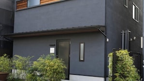 Un bâtiment moderne à deux étages, doté d’une façade sombre, de panneaux en bois décoratifs et d’une porte noire.