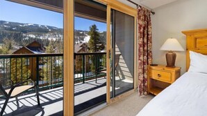 A hotel room with a balcony, a bed, a nightstand, and a view of mountains. - 4 Bedroom Condo at Gateway Lodge Near Mountain House Base (Keystone)