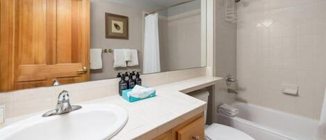 A bathroom with a wooden vanity, a sink, a mirror, a toilet, and a shower.