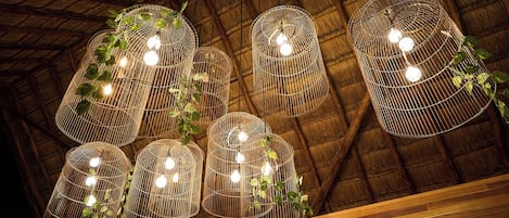 A ceiling with multiple hanging light fixtures made of woven wire, each containing a bulb.