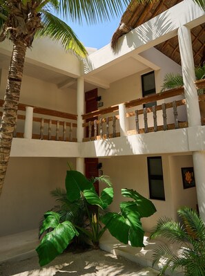 A multi-level building with balconies, large green plants, and a thatched roof.