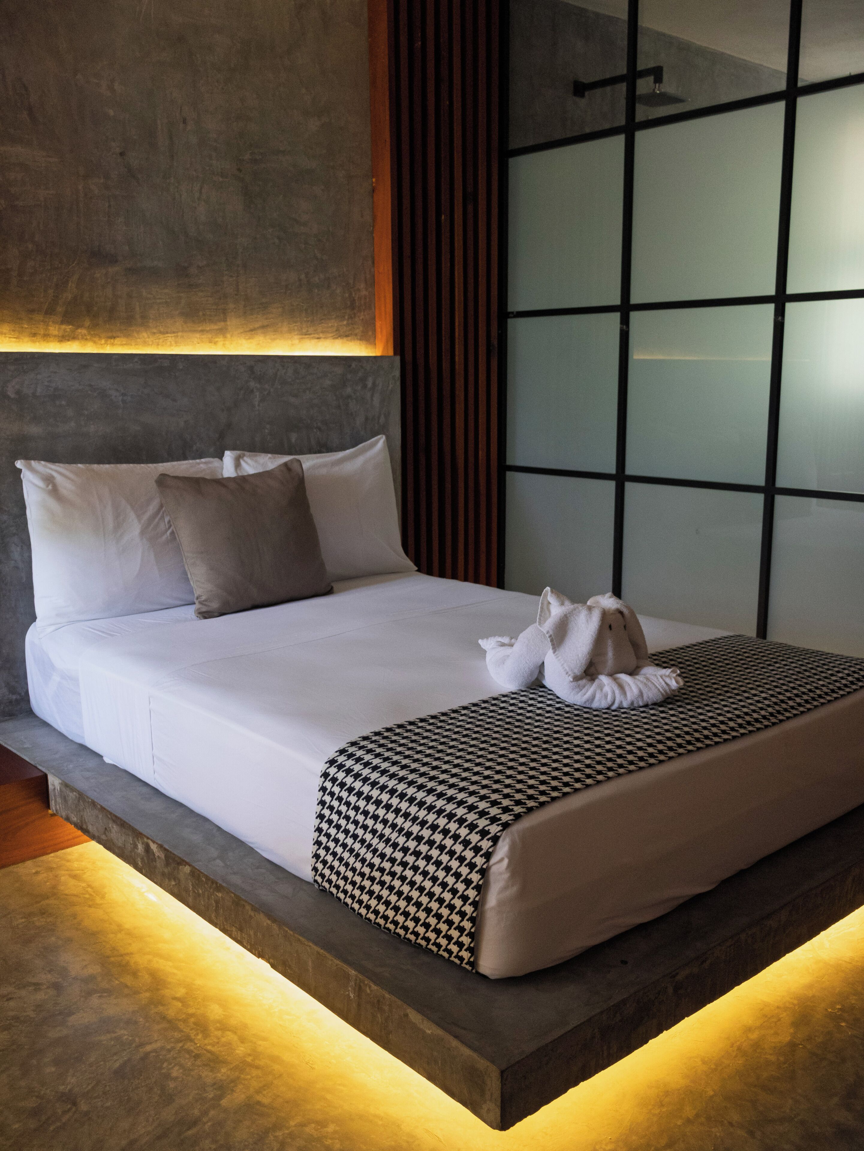 A modern hotel room with a large bed, a houndstooth throw blanket, and a towel on the bed.