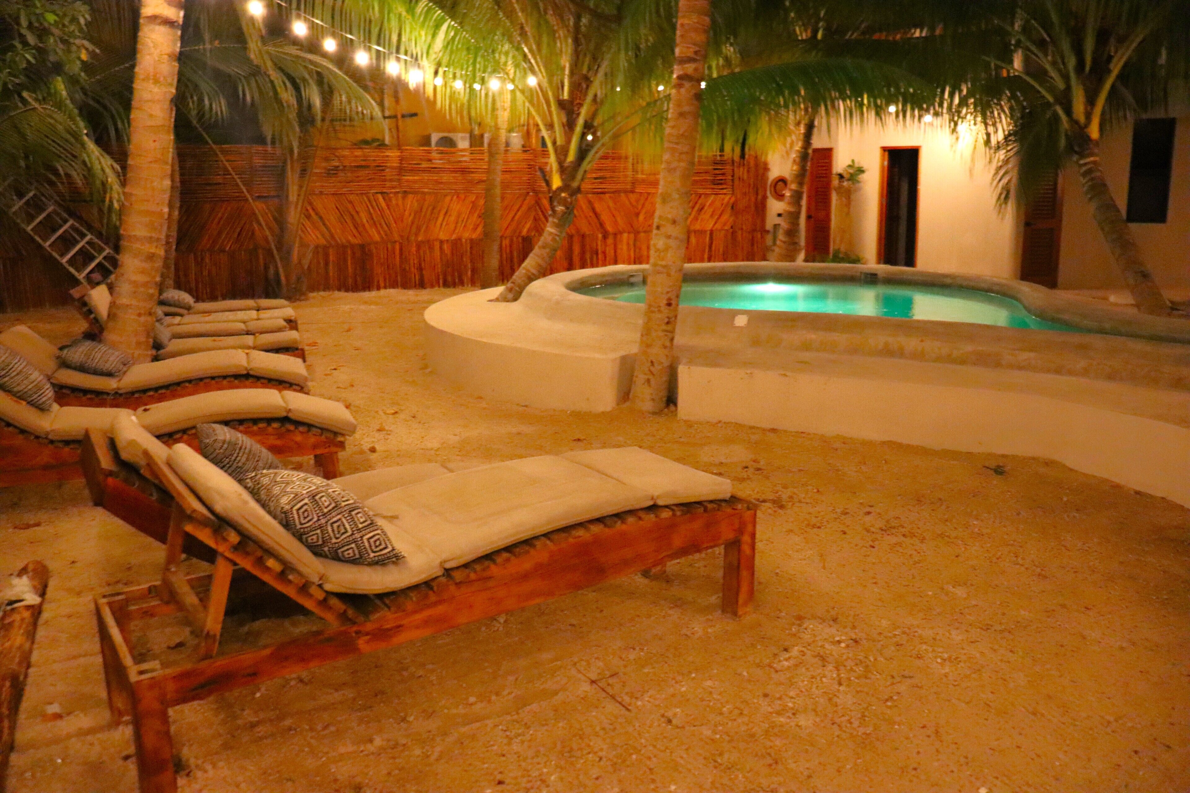 A pool area with lounge chairs and palm trees.