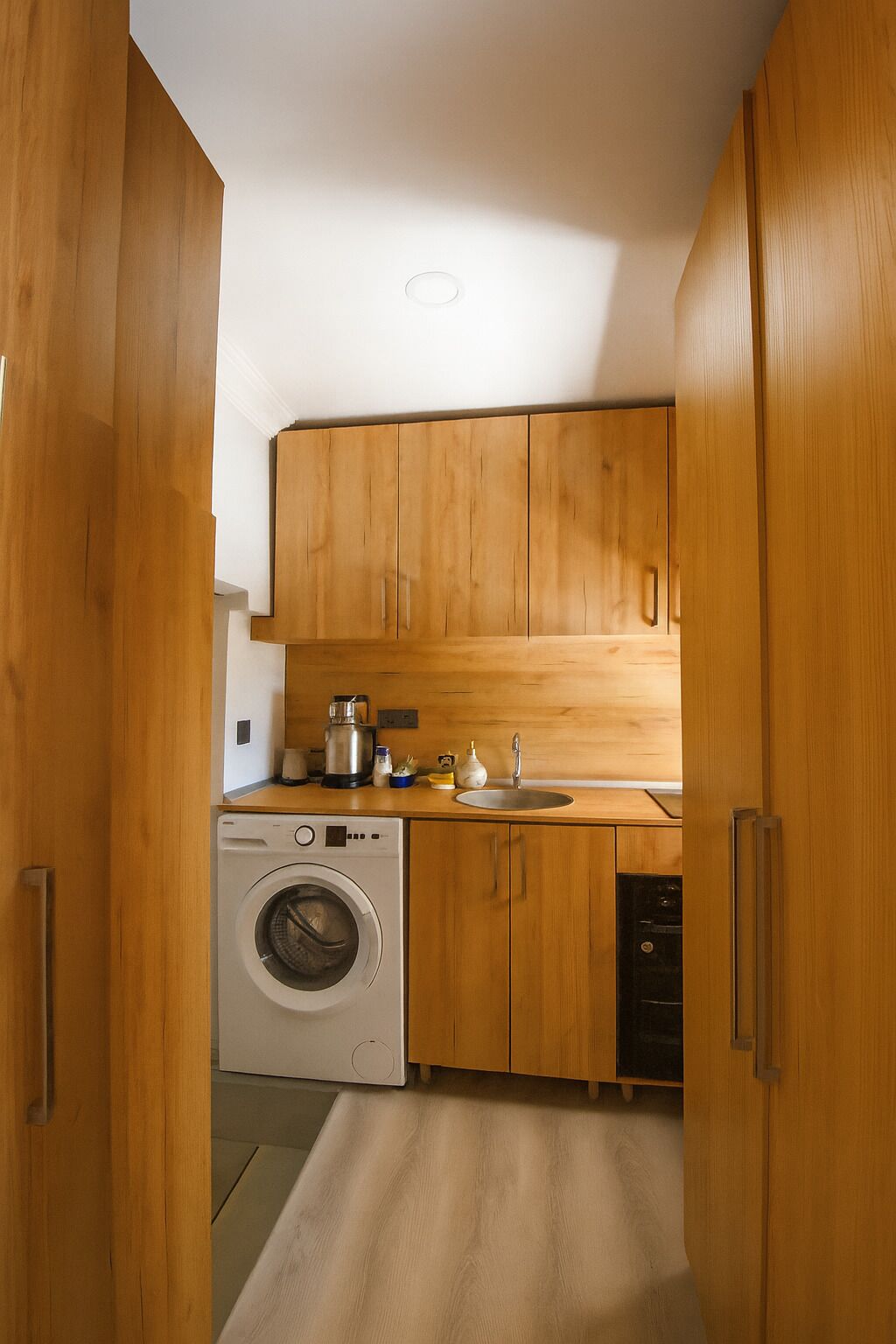 Una cocina compacta con armarios de madera, lavadora y lavavajillas.