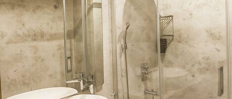 Une salle de bain moderne avec un grand miroir, deux vasques, une douche en verre et des murs en marbre.
