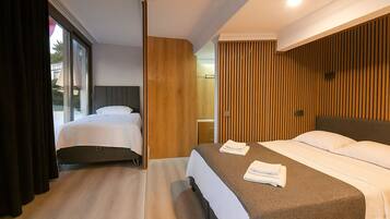 A hotel room with two beds, a large window, and a wooden accent wall.