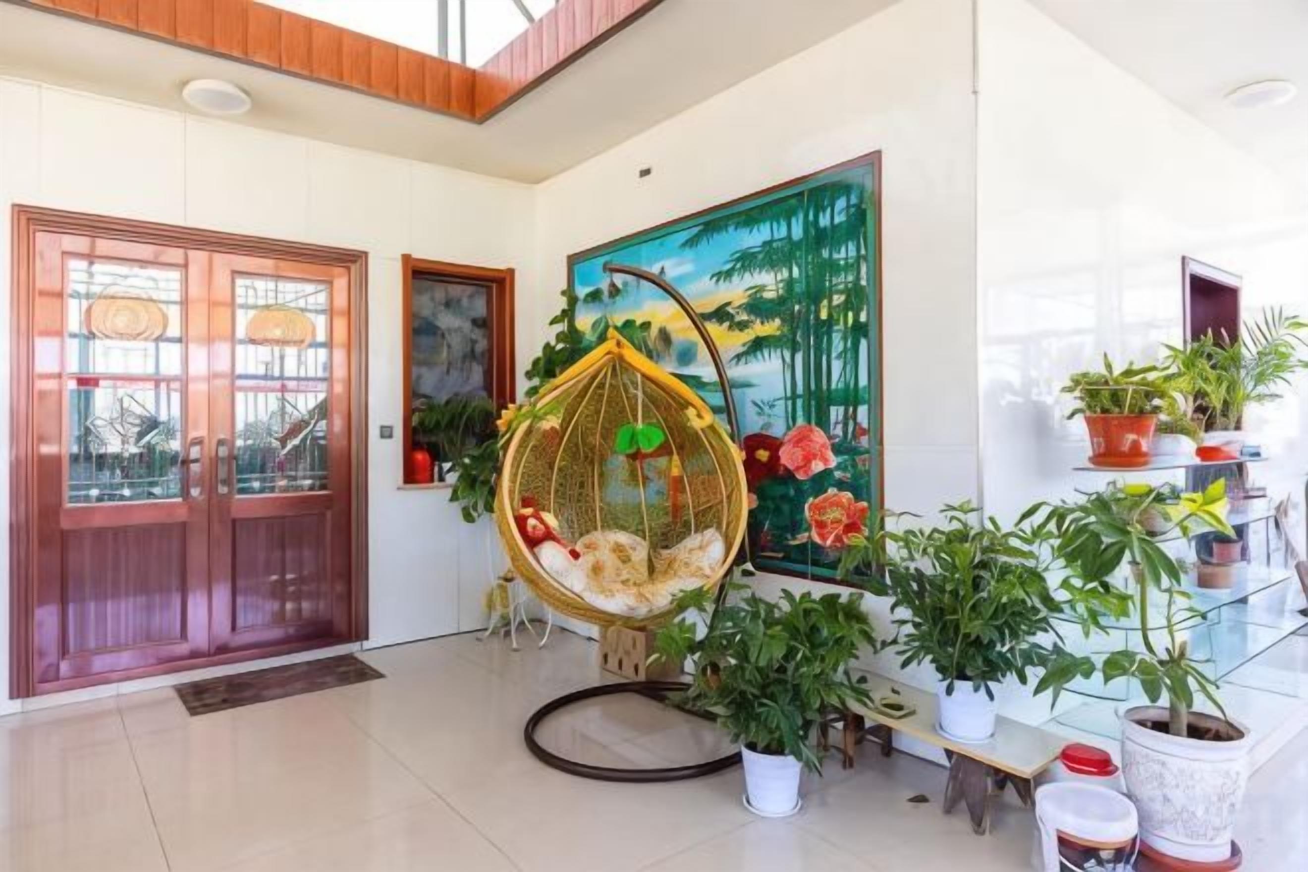 A modern interior with a wooden door, a hanging chair, and a variety of potted plants.