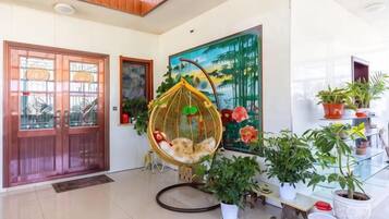 A modern interior with a wooden door, a hanging chair, and a variety of potted plants.