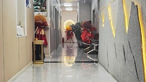 A hotel corridor with a shiny tiled floor, a reception desk, and a wall with a textured design.