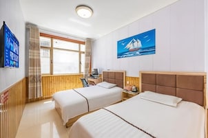 Habitación de hotel con dos camas, televisión, un cuadro de un velero y una ventana con cortinas.