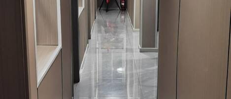A corridor with a shiny floor, flanked by walls with a light-colored finish.
