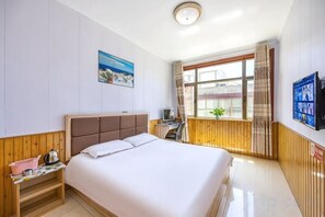A hotel room with a bed, a desk, a chair, a window with curtains, and a wall-mounted TV. - Yuzhong Senshu Business Hotel (Yuzhong)