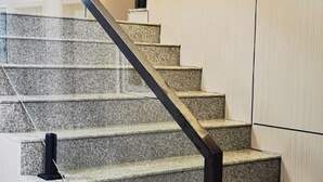A staircase with a black handrail and granite steps.