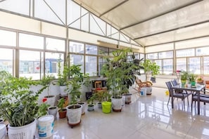 A spacious indoor area with large windows, potted plants, and a dining table. - Yuzhong Senshu Business Hotel (Yuzhong)