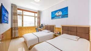 A hotel room with two beds, a desk, a chair, a TV, and a window with curtains.