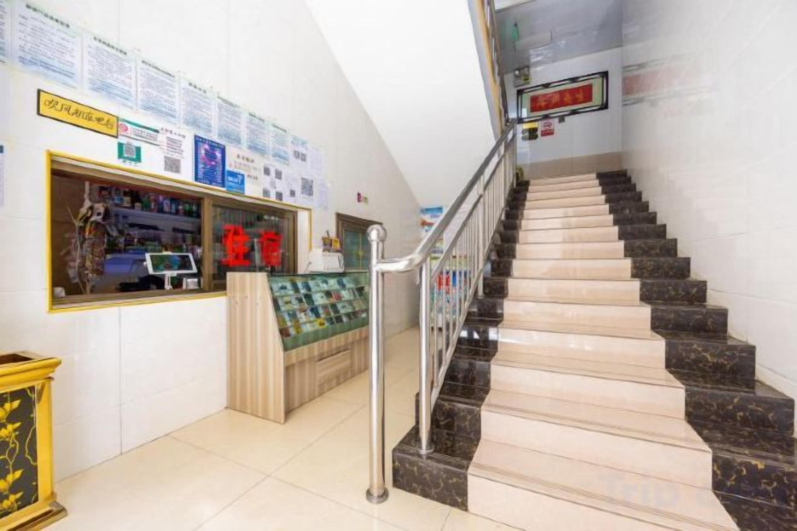 A staircase with a handrail, a reception desk with a computer, and informational posters on the walls.