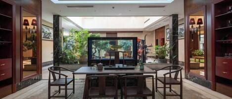 Una habitación amplia con techo alto, una araña, un televisor de pantalla plana grande y un comedor con mesa y sillas.