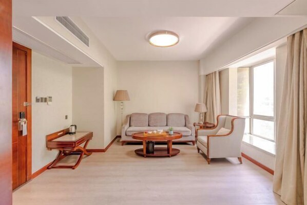 A modern hotel room with a sofa, a round coffee table, a chair, a desk, and a lamp. - Putian Pujing Hotel (Xinghuafu History and Culture Street) (Putian)