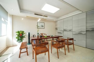 Un comedor con una mesa, sillas, una planta en maceta y una pared decorada con una pintura de montaña.