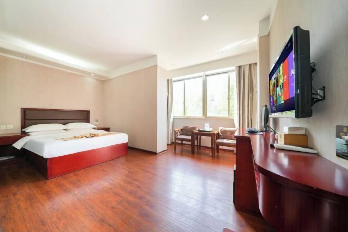 A hotel room with a bed, a desk, a chair, and a TV.