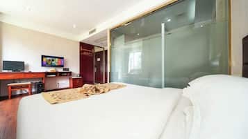 Una habitación de hotel con una cama, un escritorio con computadora, un televisor y un ventanal corredero.