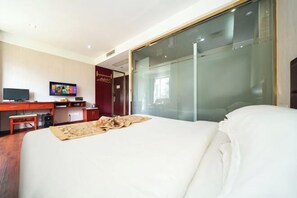 A hotel room with a bed, a desk with a computer, a TV, and a sliding glass door. - Changtai Hezheng Business Hotel (Zhangzhou)