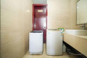 Un baño con una puerta roja, un lavabo blanco y dos electrodomésticos blancos.