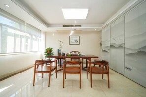 A conference room with a rectangular table and six chairs, a potted plant, and a framed picture on the wall. - Changtai Hezheng Business Hotel (Zhangzhou)