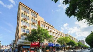A multi-story hotel with balconies, a pedestrian crossing, and various storefronts on the ground floor. - Changtai Hezheng Business Hotel (Zhangzhou)