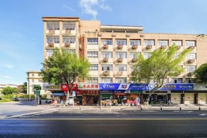 Un edificio de varios pisos con locales comerciales en la planta baja, incluyendo una farmacia y un banco.