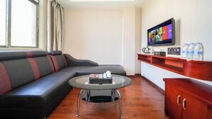 A modern living room with a sofa, a coffee table, a flat-screen TV, and a wooden cabinet. - Changtai Hezheng Business Hotel (Zhangzhou)