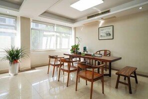 A dining area with a table and chairs, a potted plant, and a window with natural light. - Changtai Hezheng Business Hotel (Zhangzhou)