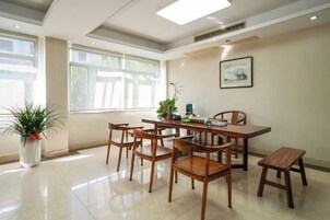 Un área de comedor con una mesa y sillas, una planta en maceta y un ventanal con luz natural.