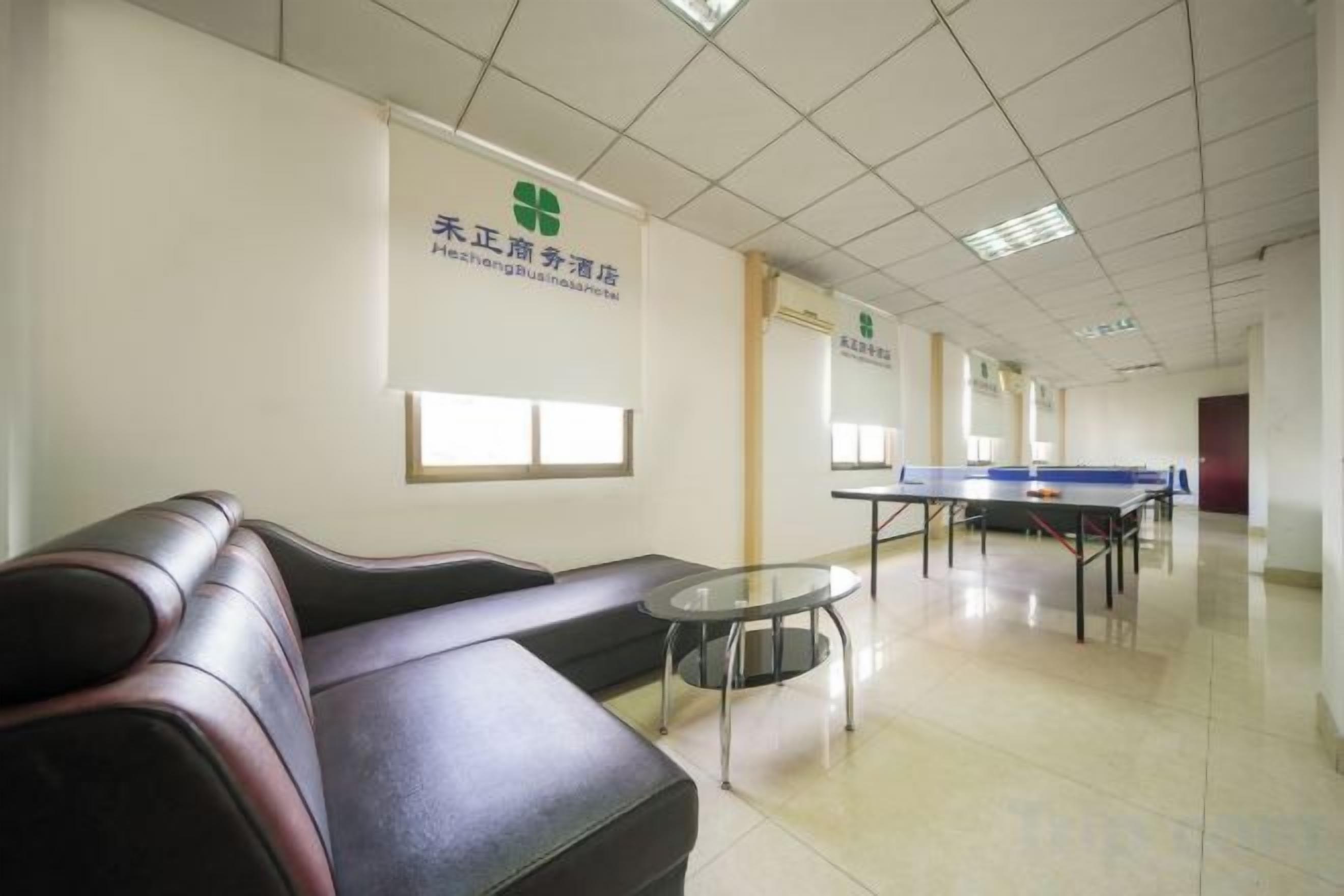 Un'area d'attesa con un divano, un tavolino e un tavolo da ping pong.