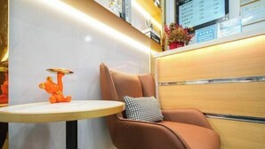 A modern hotel reception area with a leather armchair, a small round table, and a decorative orange figure on the table. - Changtai Hezheng Business Hotel (Zhangzhou)