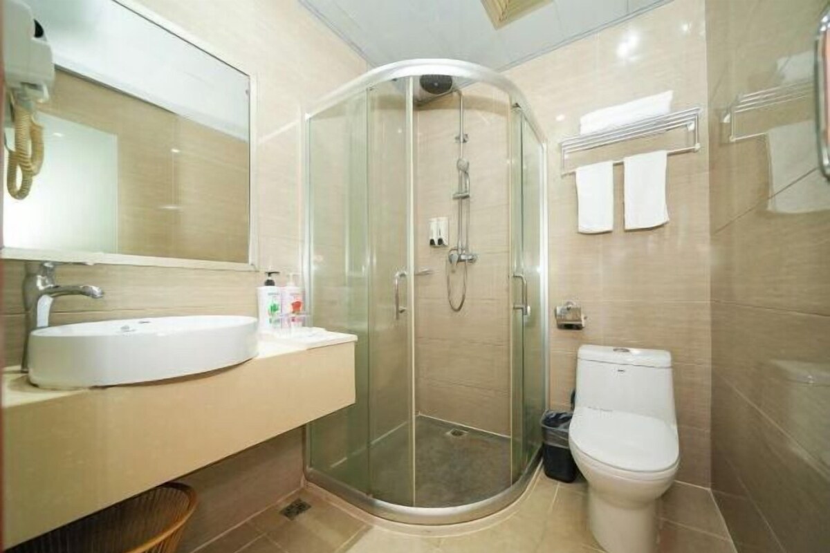 A modern bathroom with a glass-enclosed shower, a white sink, and a toilet.