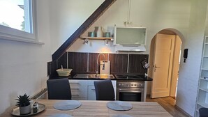Uma cozinha moderna com uma mesa de madeira, duas cadeiras, um fogão e uma pia.
