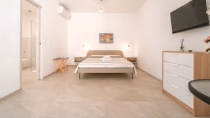 A modern bedroom with a bed, bedside tables, a TV, and a small desk.