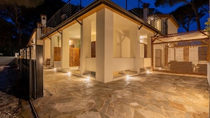 A modern house with a stone patio, large windows, and a balcony.