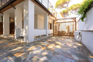 A stone-paved courtyard with a wooden deck, white walls, and a metal railing.
