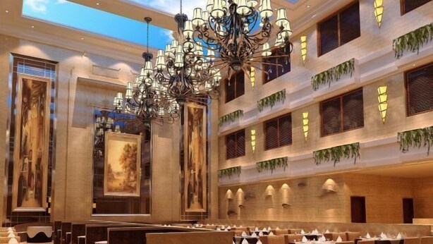 A spacious hotel lobby with multiple dining areas, a grand chandelier, and artwork on the walls. - Western Regions Spring Hotel (Wensu)