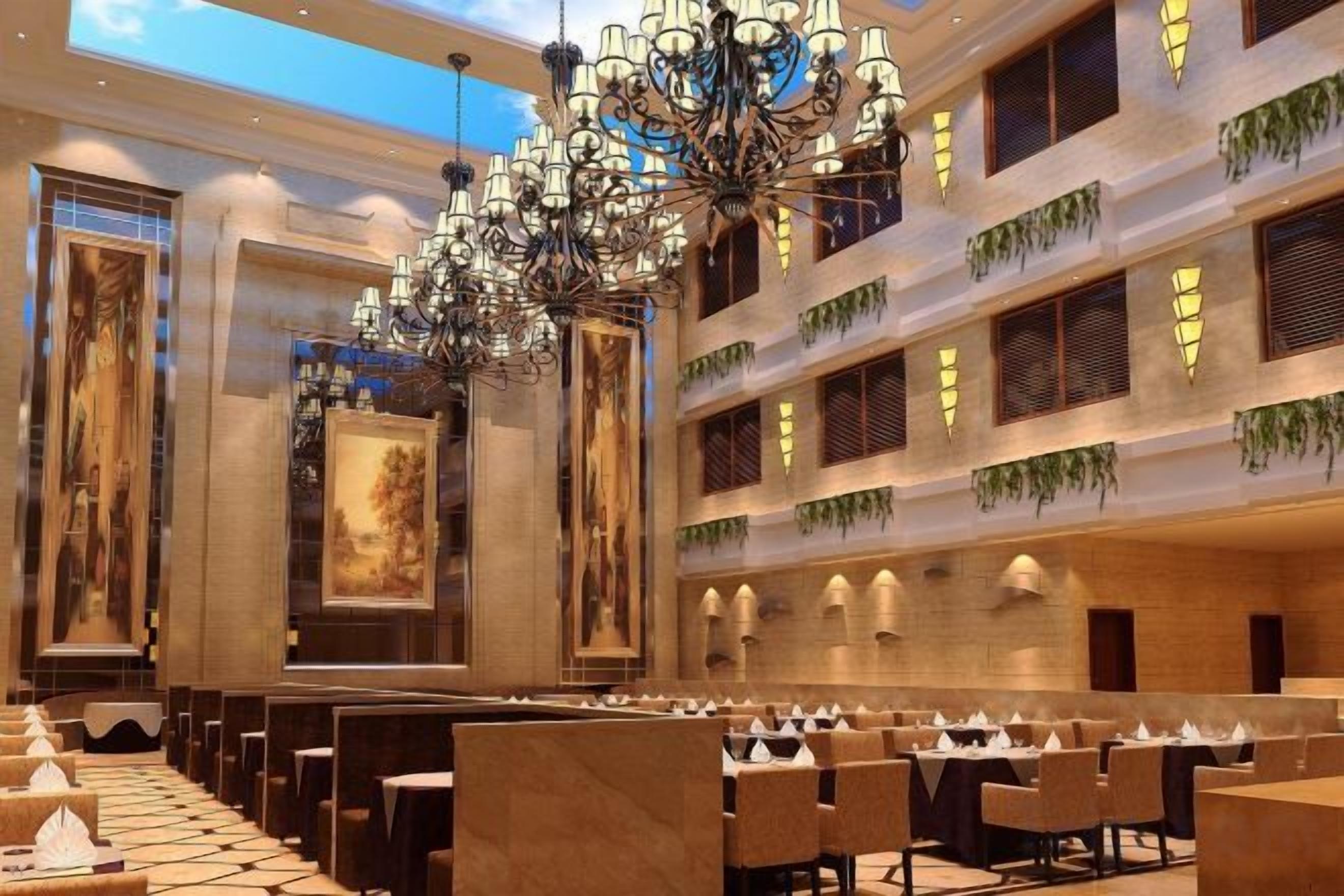 A spacious hotel lobby with multiple dining areas, a grand chandelier, and a high ceiling.