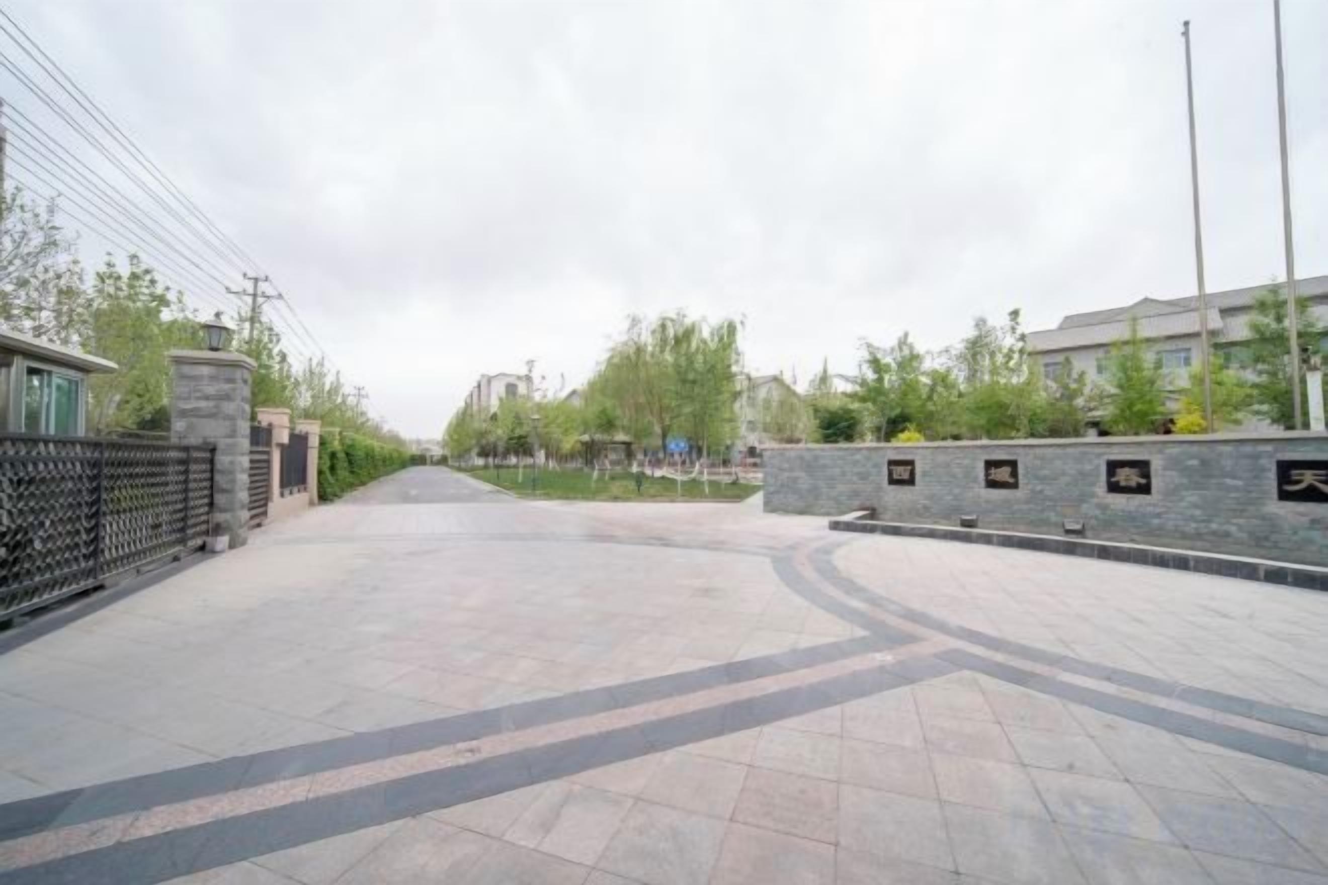 Un vialetto lastricato con un muro in pietra da un lato e una recinzione dall'altro, che conduce a un edificio con tetto piano.