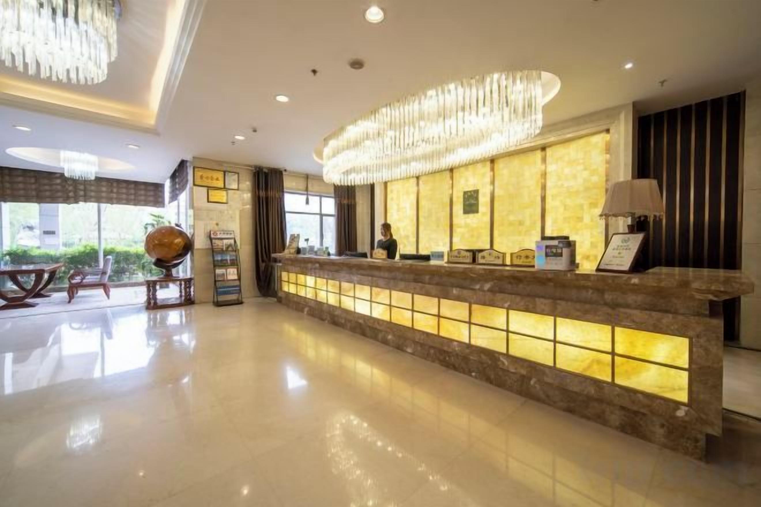 A hotel reception area with a marble counter, a globe, and a seating area with a table and chairs.