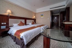 Een hotelkamer met twee bedden, een glazen tafel en een houten hoofdeinde.