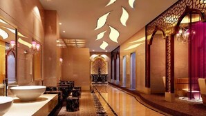 A modern hotel lobby with a long reception desk, a large mirror, and a seating area with a patterned rug. - Western Regions Spring Hotel (Wensu)