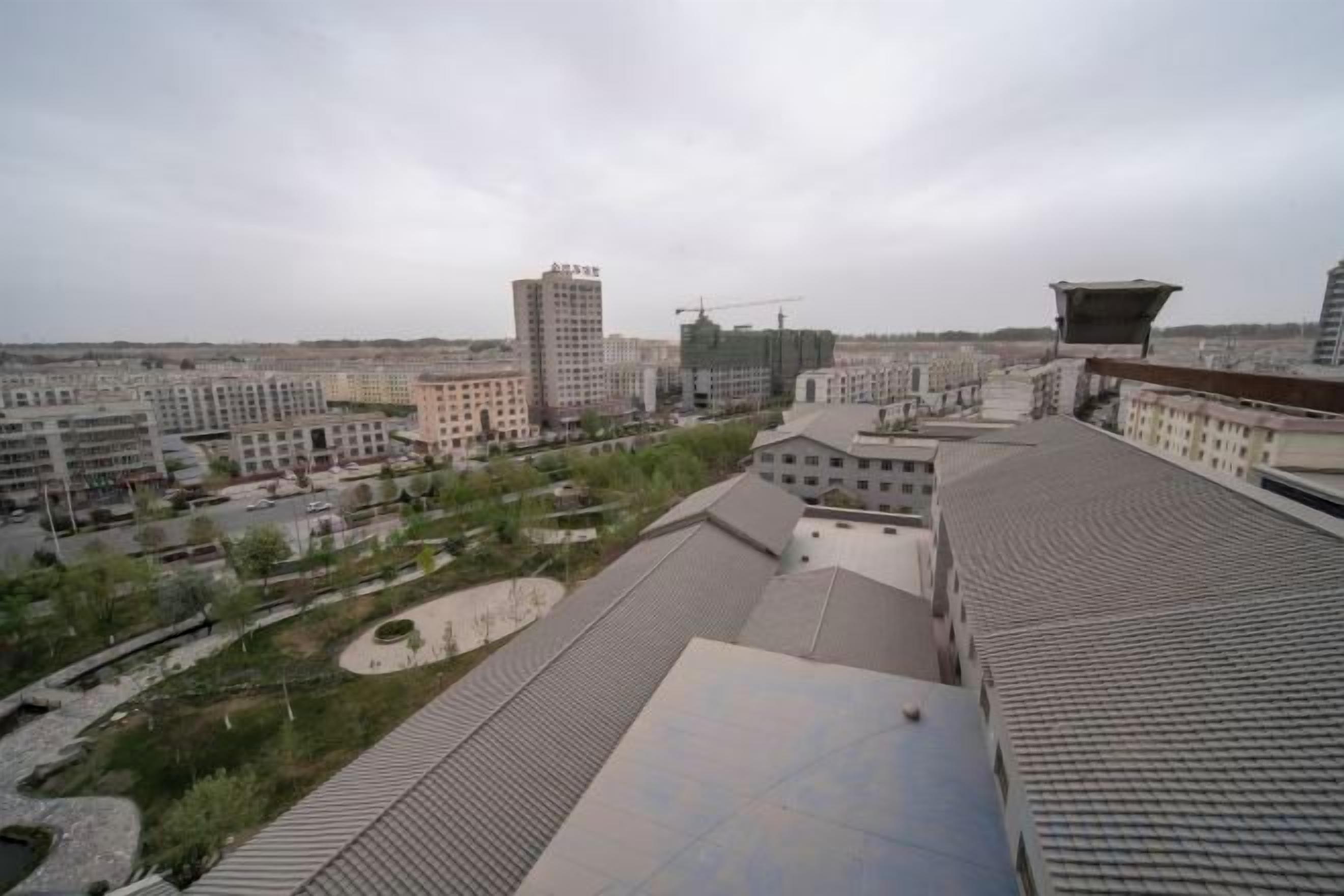Un paisaje urbano con edificios modernos, una grúa de construcción y una gran plaza abierta.