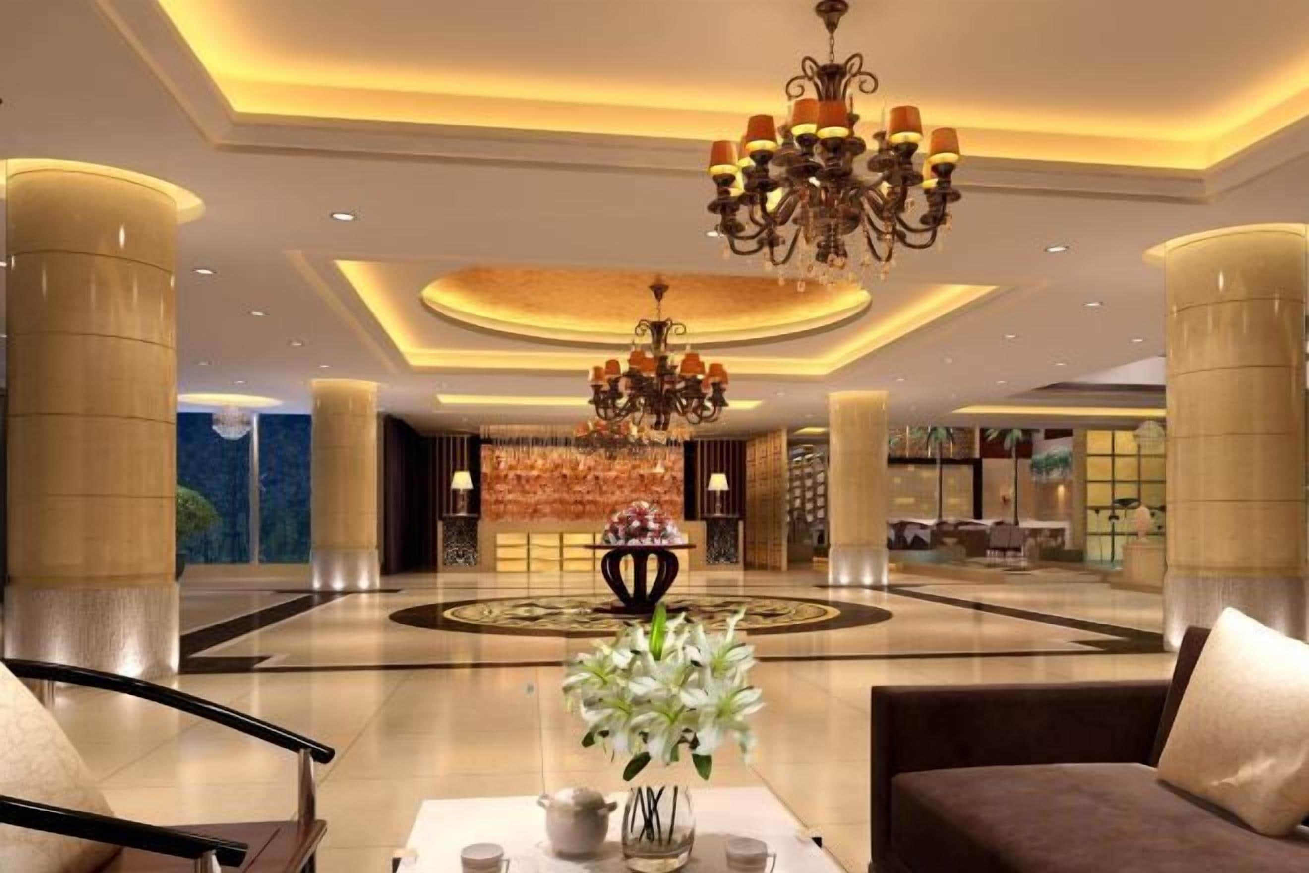 A hotel lobby with a chandelier, seating area, and a reception desk.