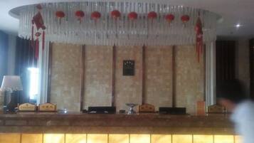 Un'area di accoglienza con reception, orologio a parete e soffitto decorato.